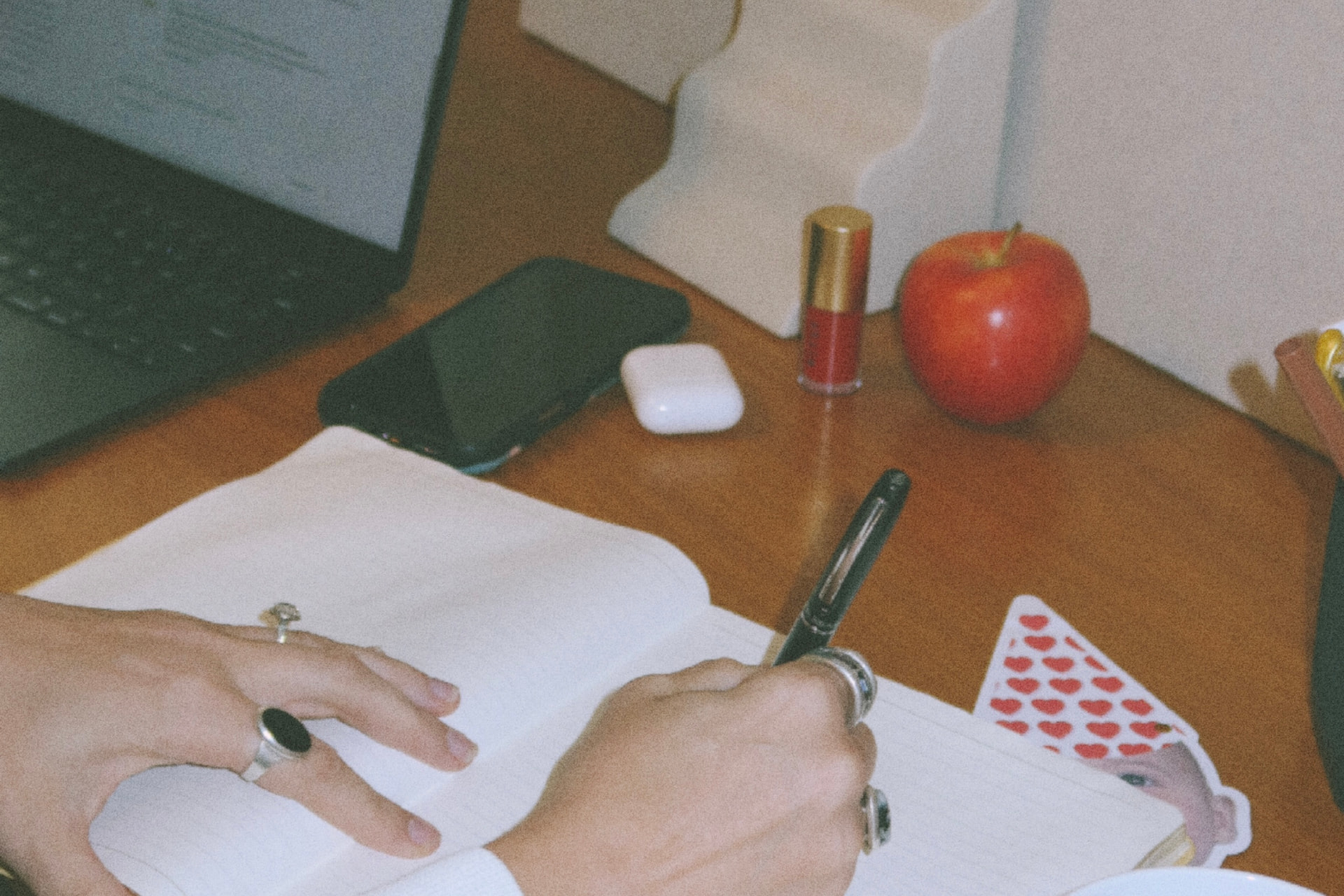 A mother's kitchen table with an open laptop, a notebook of handwritten notes and a cup of coffee